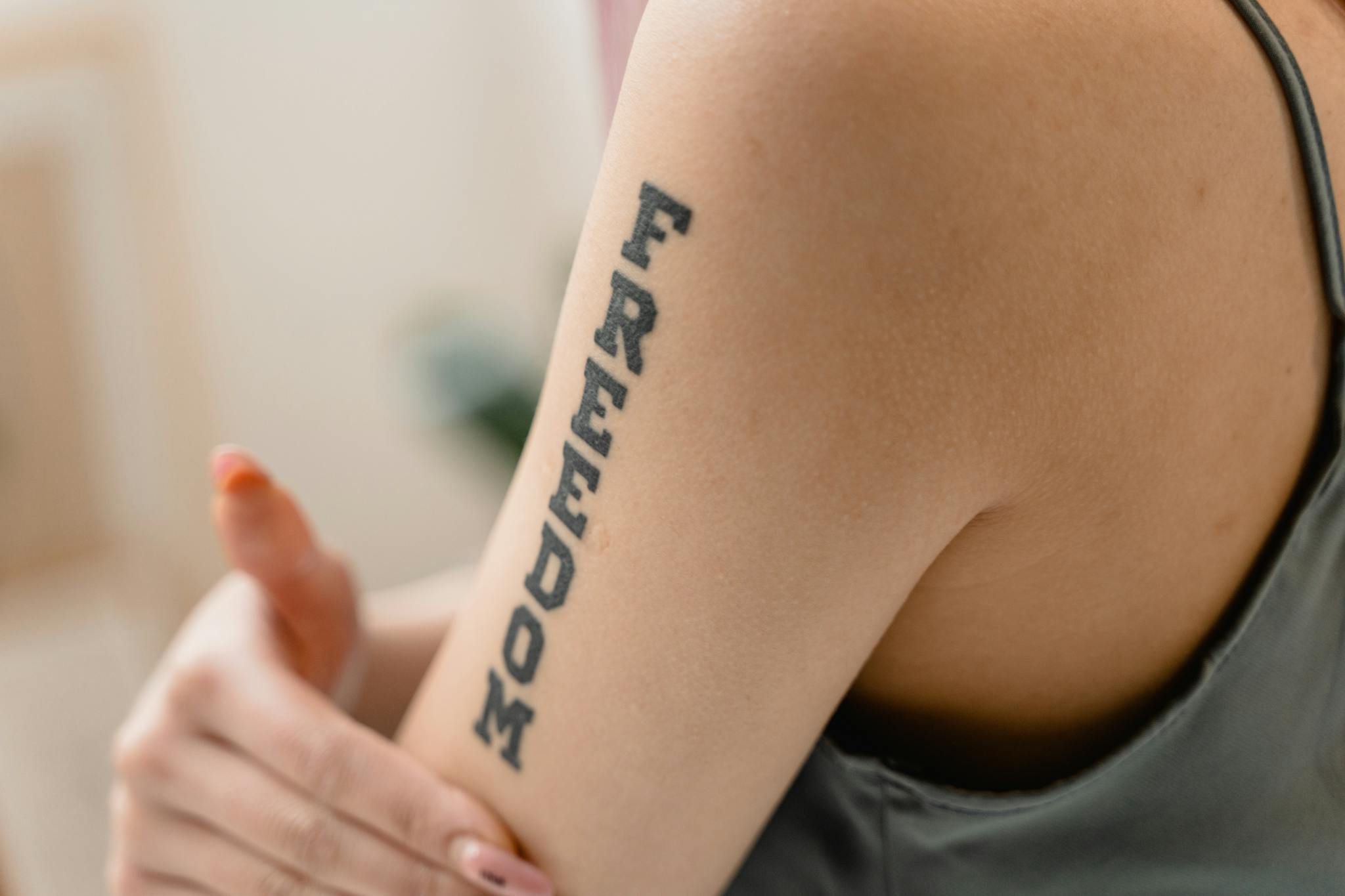 A close-up view of a 'Freedom' tattoo on a woman's arm, symbolizing independence and strength.