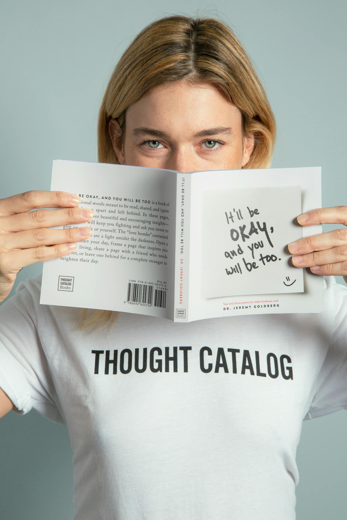 Woman in t-shirt holding a book with a motivational quote, creating an encouraging atmosphere.